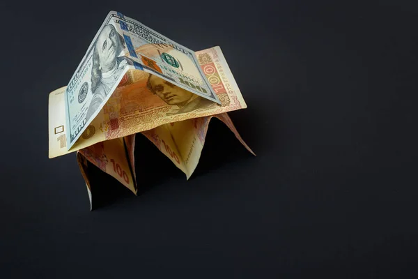 Дом счетов. У дома есть крыша из долларовых купюр. Счета на тёмном столе. . — стоковое фото