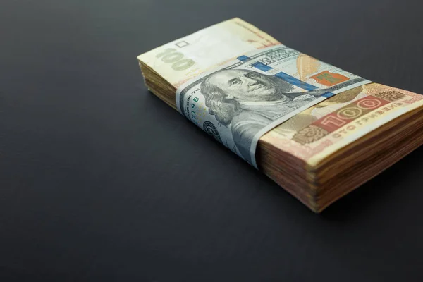 Стоимость украинской гривны и американских долларов. Пачка украинских гривен обернулась стодолларовой купюрой — стоковое фото