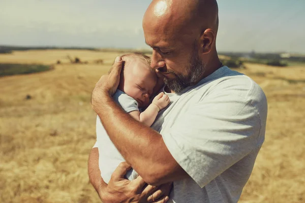 年轻的爸爸抱着一个新生婴儿，而走在大自然。快乐的父亲穿着短裤和T恤。国际父亲节 — 图库照片
