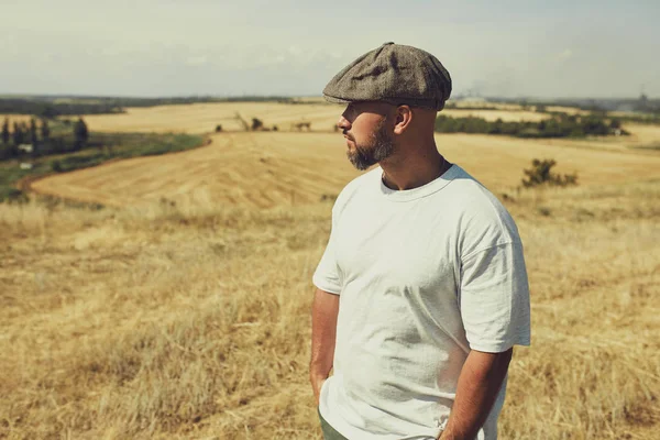 Uomo in t-shirt e cappello sullo sfondo dei campi di cereali — Foto Stock