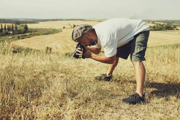 Humorvolles Konzept. ein sehr emotionaler Fotograf fotografiert etwas am Boden. Gefühl der Überraschung auf seinem Gesicht — Stockfoto