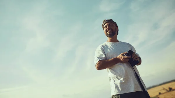 Fotografo con una macchina fotografica tra le mani contro il cielo in un caldo, afoso giorno. Posto per testo, sfondo, carta da parati . — Foto Stock