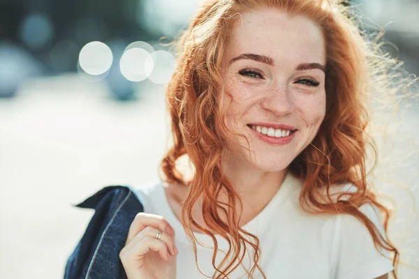 Schöne rothaarige Mädchen, die Spaß auf der Straße haben. die Mädchen haben eine schöne Figur, ein weißes T-Shirt und Jeans mit Sonnenbrille Stockfoto