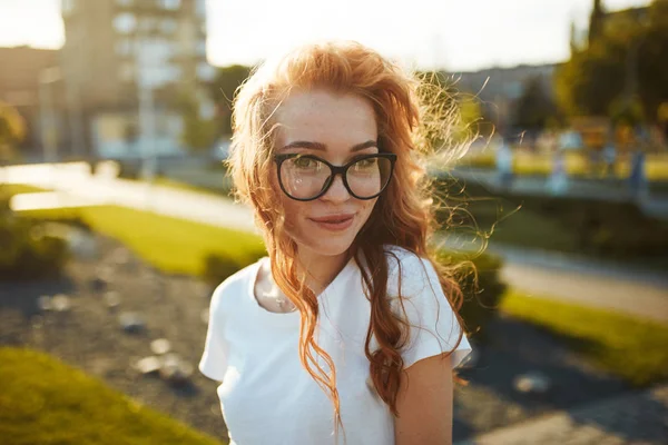 Retratos de una encantadora chica pelirroja con una cara linda. Chica posando para la cámara en el centro de la ciudad. Tiene un humor maravilloso y una sonrisa encantadora. —  Fotos de Stock