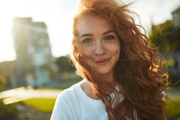 Porträts eines charmanten rothaarigen Mädchens mit einem niedlichen Gesicht. Mädchen posieren in der Innenstadt für die Kamera. Sie hat eine wunderbare Stimmung und ein schönes Lächeln — Stockfoto