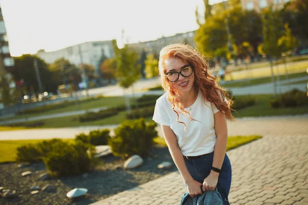 Porträtt av en charmig rödhårig flicka med ett sött ansikte. Flickan poserar för kameran i stadens centrum. Hon har ett underbart humör och ett underbart leende. — Stockfoto