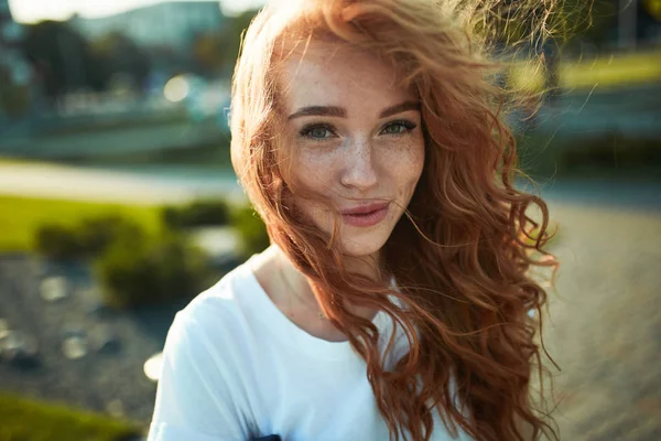 Retratos de una encantadora chica pelirroja con una cara linda. Chica posando para la cámara en el centro de la ciudad. Tiene un humor maravilloso y una sonrisa encantadora. — Foto de Stock