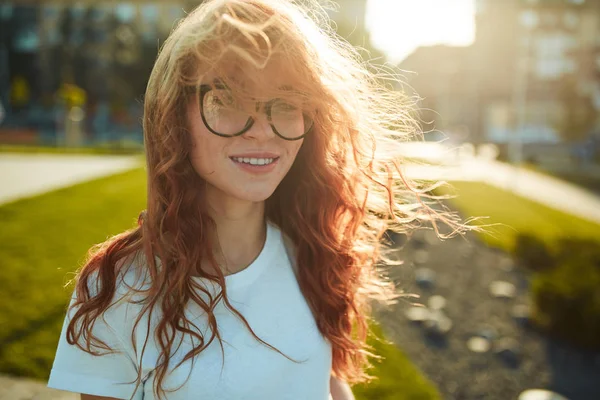 Porträtt av en charmig rödhårig flicka med ett sött ansikte. Flickan poserar för kameran i stadens centrum. Hon har ett underbart humör och ett underbart leende. — Stockfoto