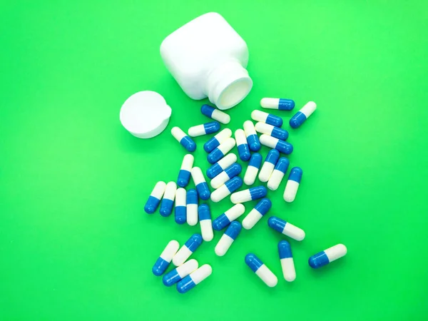 Pills isolated on a green background. Set of tablets in capsules.  A kit of medical  pills for treatment. Pack of pills, capsules. Bottle with pills.