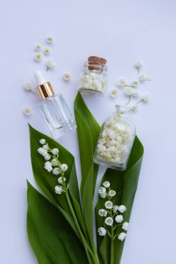 Cam bir şişe vadi zambağı taze çiçeklerle birlikte gerekli yağ. Düz yatıyordu