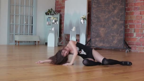 Молодая женщина в развратной одежде танцует на полу — стоковое видео