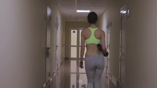 Спортивная женщина, идущая по коридору — стоковое видео