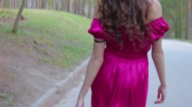 Arkadan görünümü kamera güzel park sokakta boyunca uzağa yürüme parlak içinde genç kadın