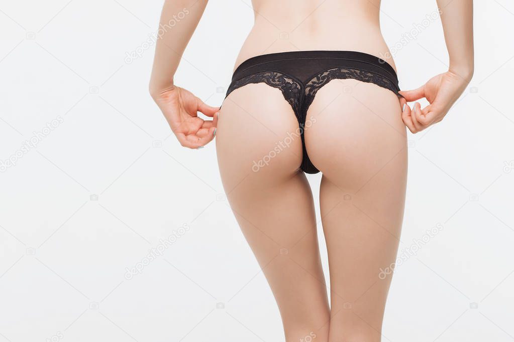 Crop side view of faceless naked female standing and keeping hands on thong