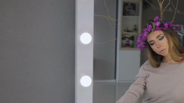 Женщина в цветочном венке стоит с зеркалами позади — стоковое видео