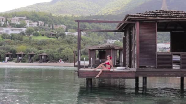 Girl in Bungalow on the water — Stock Video