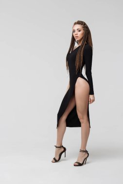 Siyah elbise şaşırtıcı ve kamera ışık gri arka plan üzerinde dururken bakarak uzun dreadlocks ile şehvetli genç erkek yan görünüm