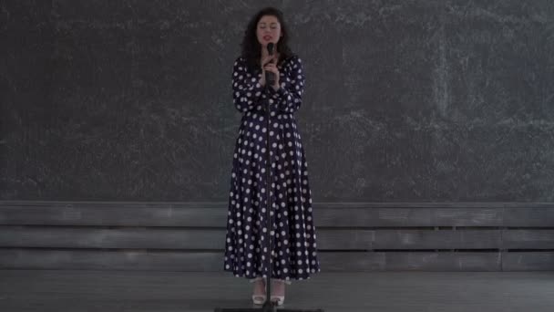 Прелестная молодая женщина, поющая под микрофон — стоковое видео