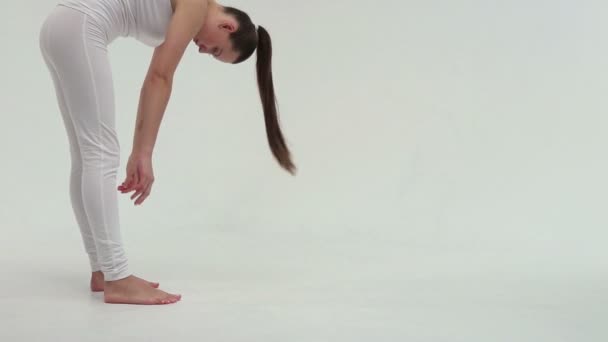 La joven mujer atlética encantadora haciendo el puente lateral en la alfombra de ejercicio en el fondo blanco . — Vídeos de Stock