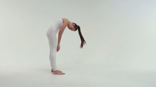A jovem mulher esportiva encantadora fazendo a ponte lateral no tapete de exercícios no fundo branco . — Vídeo de Stock