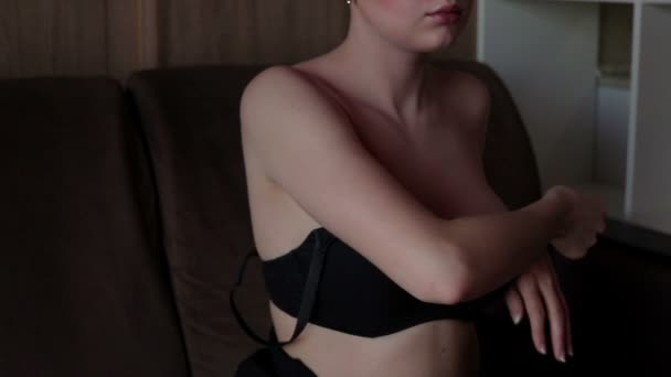 Sensual mujer poniéndose el sujetador en el sofá — Vídeo de stock