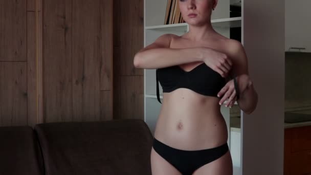 Sensual woman putting on bra on sofa — Stock Video
