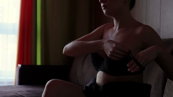 Чуттєва жінка одягає бюстгальтер на диван — стокове відео