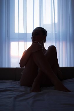 Genç seksi çıplak kadın yatakta karanlık odada poz