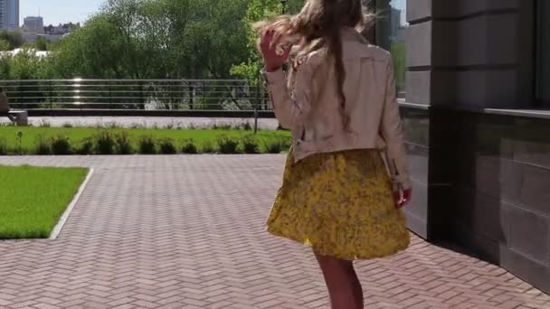 La chica elegante y atractiva pasea por la ciudad a lo largo de las tiendas — Vídeos de Stock