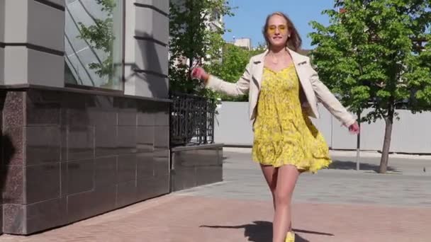 Стильная и привлекательная девушка прогуливается по городу вдоль магазинов — стоковое видео