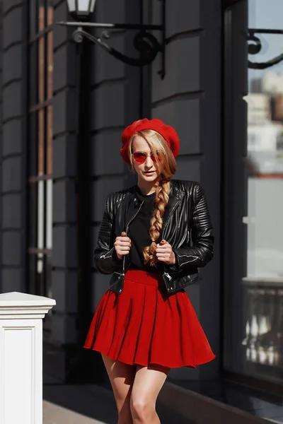 Porträt der schönen jungen blonden Frau in stylischem schwarzen Outfit, sie lächelt auf städtischem Hintergrund — Stockfoto