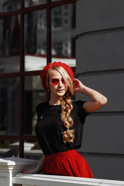 Porträt der schönen jungen blonden Frau in stylischem schwarzen Outfit, sie lächelt auf städtischem Hintergrund — Stockfoto