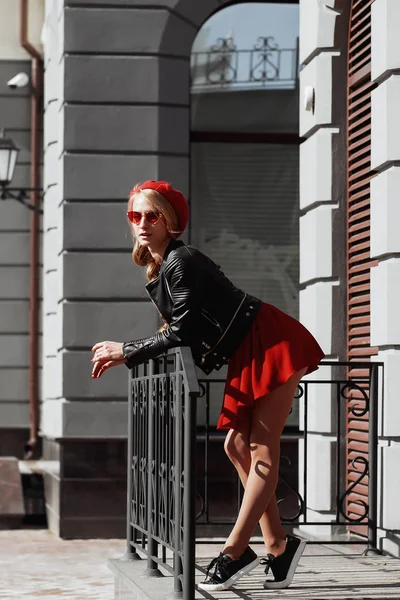 Portrait of beautiful young blonde woman wearing stylish black outfit, she smiling on urban background — Stock Photo, Image