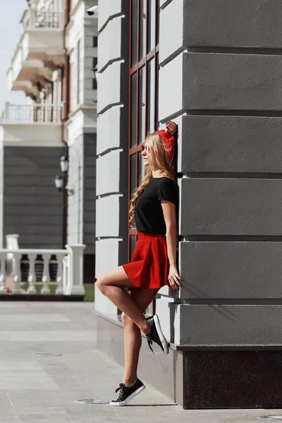 Portrait de belle jeune femme blonde portant une tenue noire élégante, elle sourit sur fond urbain — Photo