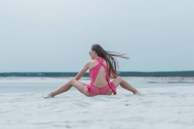 Seksi uzun saçlı kadın oturma ile Leg Apart üzerinde deniz kenarı
