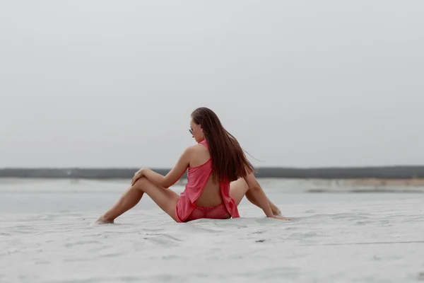 Sexy femme aux cheveux longs assis avec jambe écartées sur le bord de la mer — Photo
