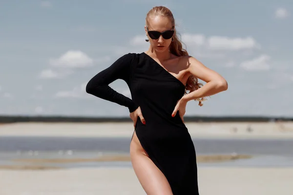 Mujer atractiva en elegante vestido negro en la playa — Foto de Stock