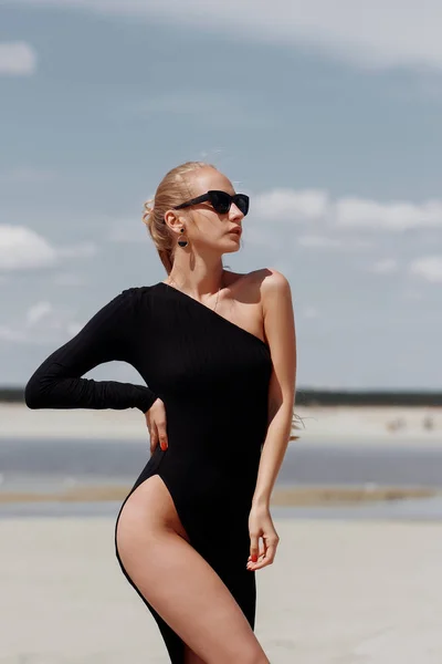 Aantrekkelijke vrouw in elegante zwarte jurk op strand — Stockfoto