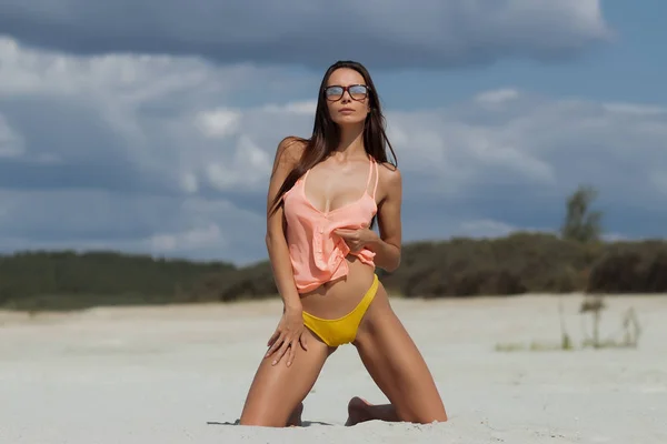 Sensuele vrouw knielende op het strand — Stockfoto