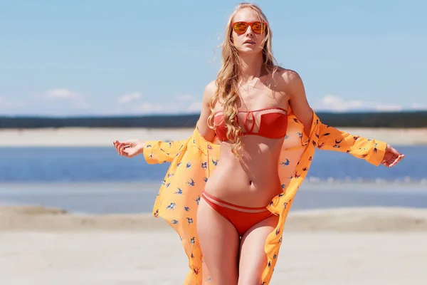 海辺で髪に触れる明るい水着でトレンディな女性 — ストック写真