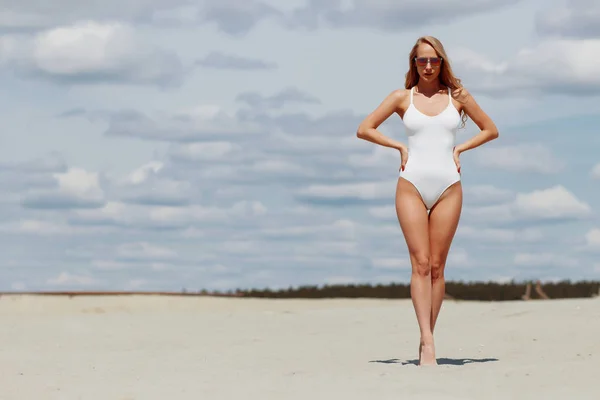 Pewnie seksowna Kobieta w uwodzicielska postawa ciągnie stroje kąpielowe na plaży — Zdjęcie stockowe
