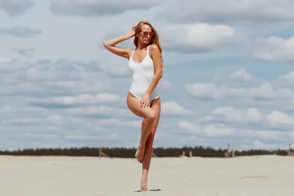 Confident sexy woman in seductive posture pulling swimwear on beach — Stock Photo, Image