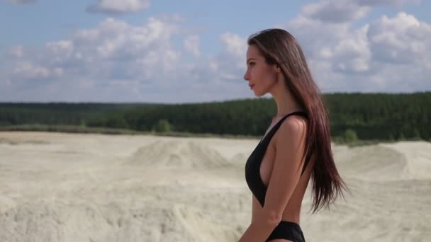 해변을 따라 걷는 검은 수영복을 입은 아름다운 여성 — 비디오