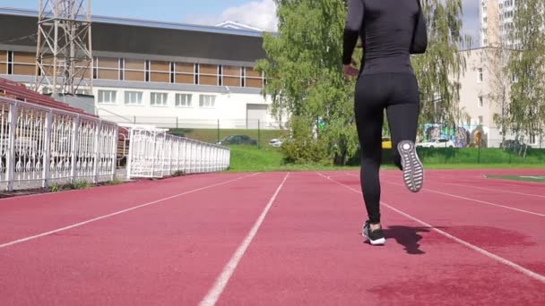 Slim woman running on racetrack in sunshine — Stock Video