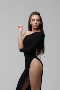 Açık gri arka plan üzerinde duran zarif elbise dreadlocks ile kadın