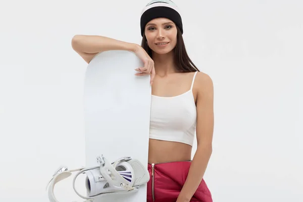 Aktív nő nyitott síöltönyben, snowboarddal a kezében, kamerába néz — Stock Fotó