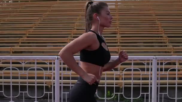 Slim woman running in city stadium — Stock Video