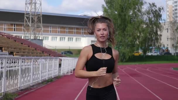 Slanke zweterige vrouw die op atletisch veld draait — Stockvideo