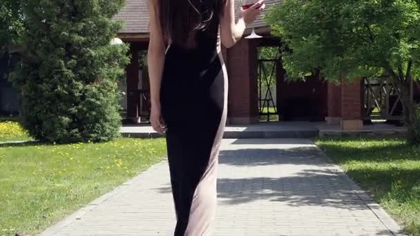 Elegáns nő üveg borral sétál a kastély kertjében — Stock videók