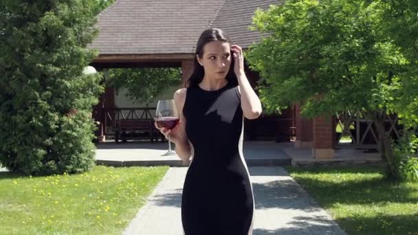 Femme élégante avec verre de vin marchant dans le jardin du manoir — Video